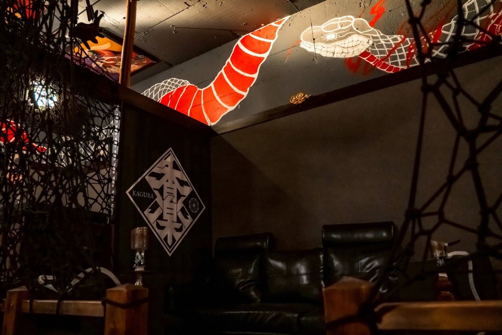 大蛇の壁画と縄のアートを望む香楽本店のソファ席