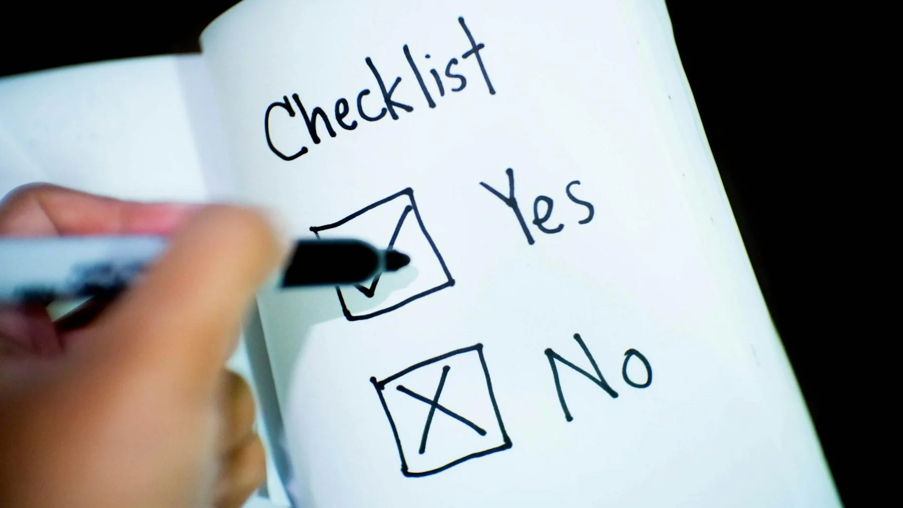 person marking check on opened book