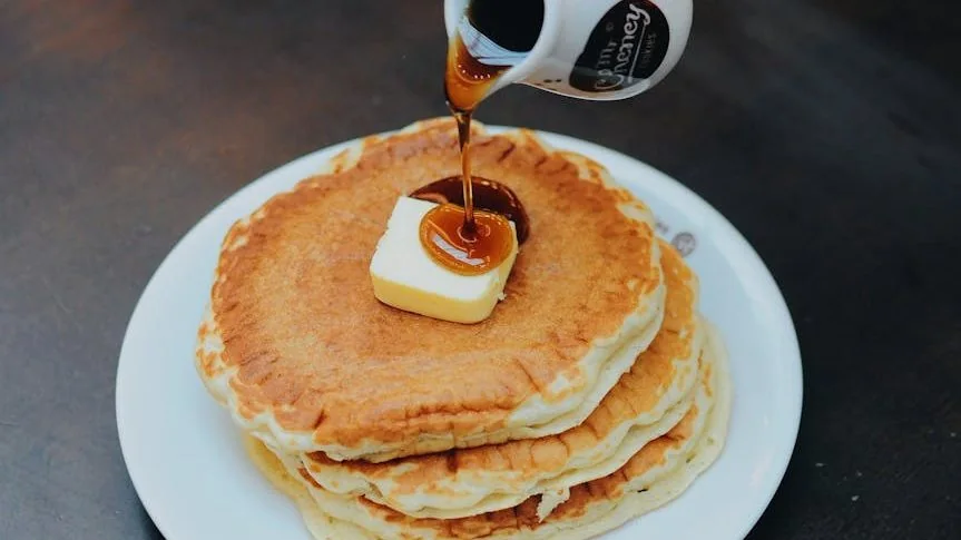 person pouring syrup on pancake